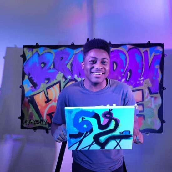 Young man holding his artwork with a purplish-blue artsy background