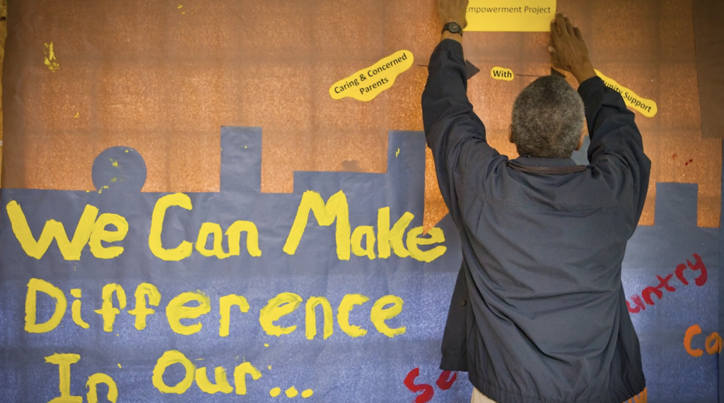 Man places affirmational messages next to wall mural that says "We Can Make a Difference"